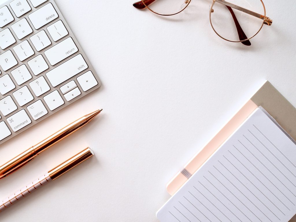 A white desk with glasses and a keyboard