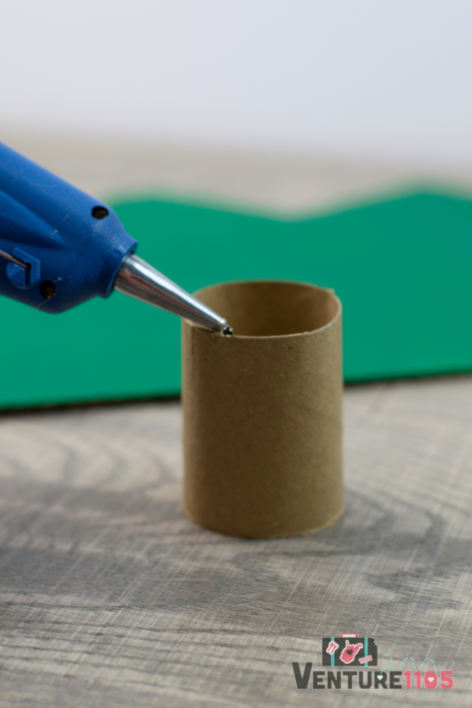 Adding hot glue to a cardboard roll.