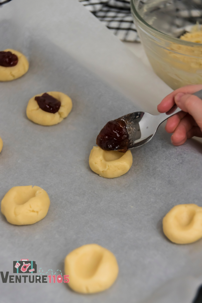 Adding jam to the top of the cookies 