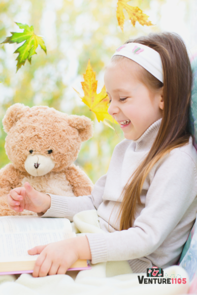A child reading a book with her teddy bear