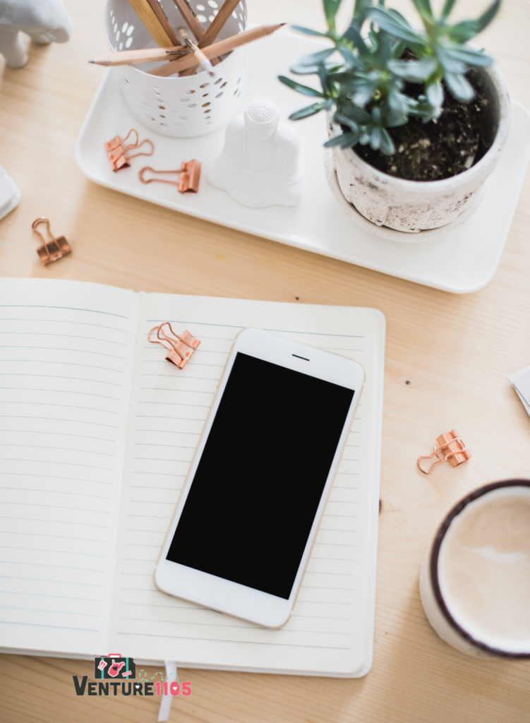 A flat lay of a phone on top of a notebook
