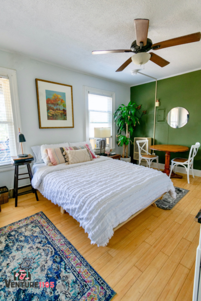 A bedroom with a green wall and a blue rug