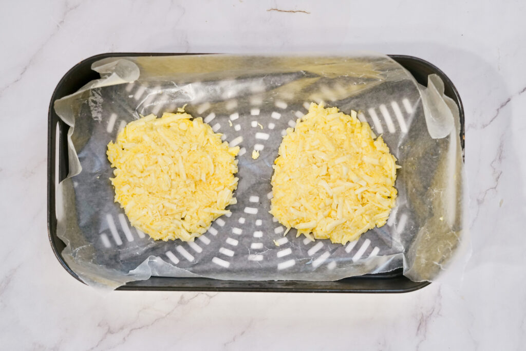 Placing the uncooked keto pizza crust on the bottom of the air fryer basket 